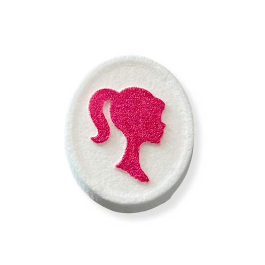 A bath bomb with a silhouette of a girl in pink on the top, set against a white background.